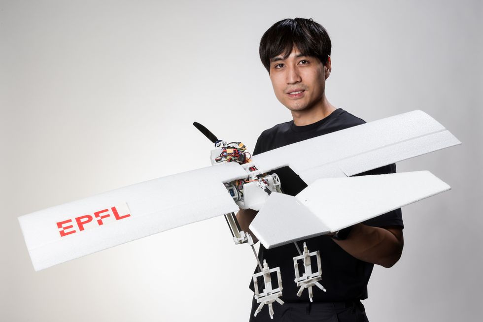 A man holding a drone with "EPFL" on the wing.  